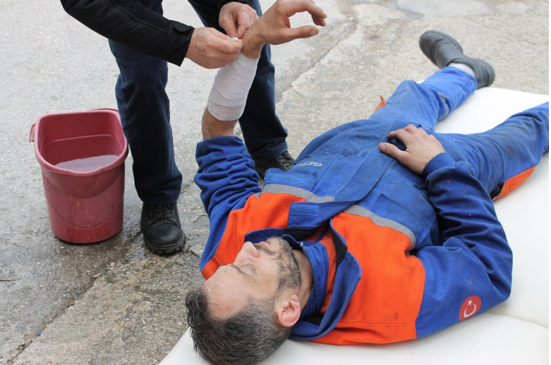 Injured Man lying on the Ground receving a First Aid Treatment 