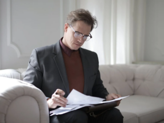 Alt-Text: Classy executive male reading papers on couch