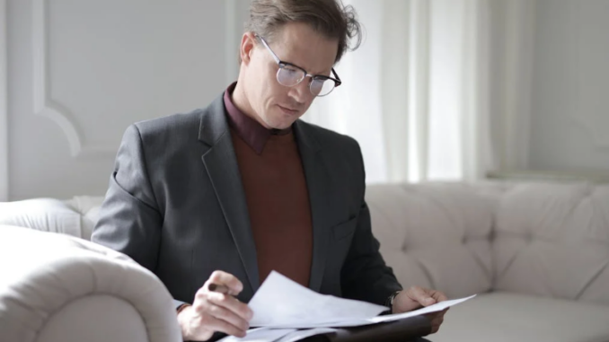 Alt-Text: Classy executive male reading papers on couch