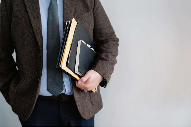 Alt-Text: Crop unrecognizable office worker standing with papers in hand