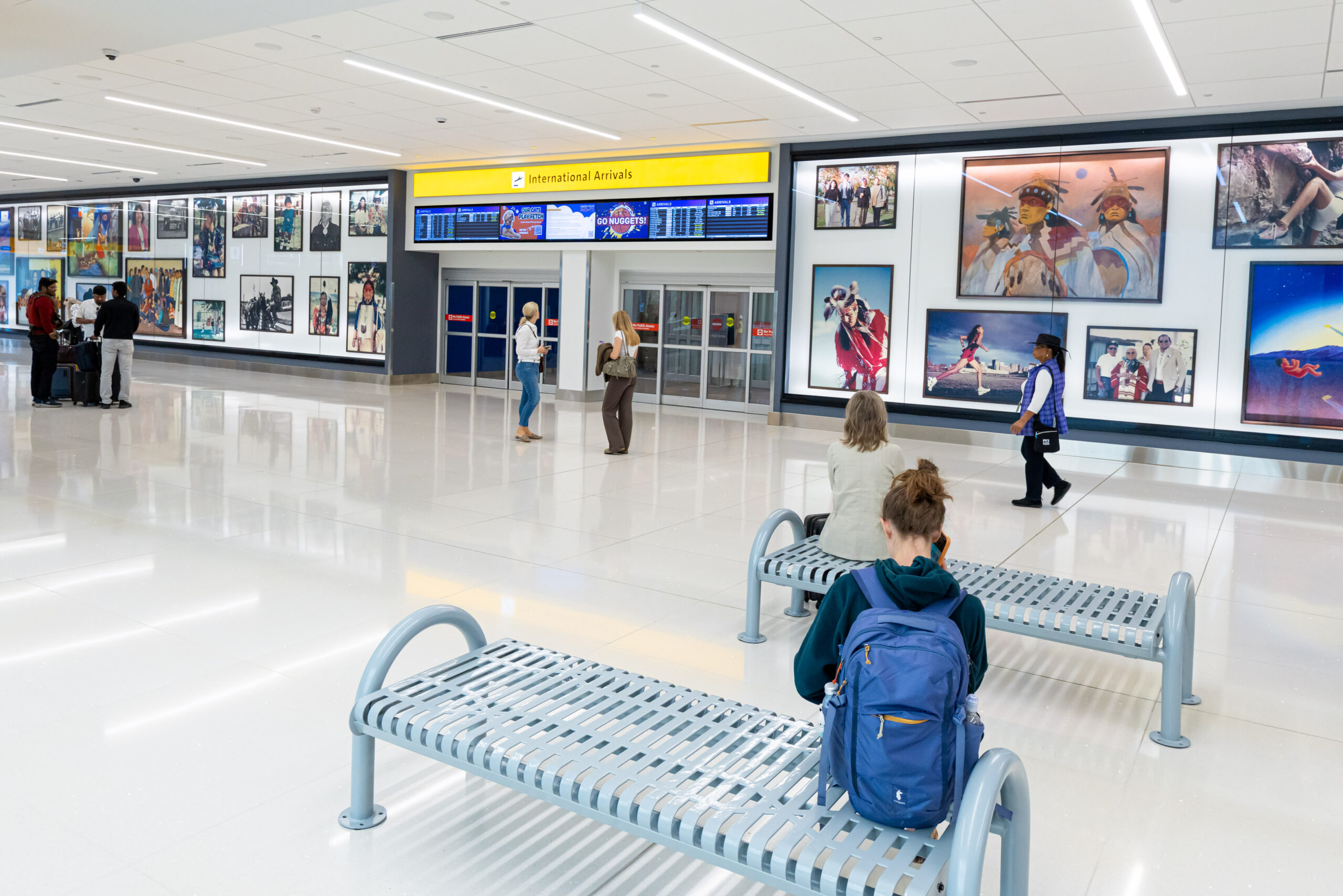 Newly renovated international arrivals area at Denver International Airport with seating, travelers and public artwork.
